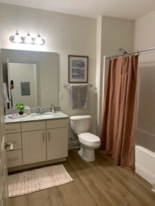 bathroom, large vanity mirror, bathtub/shower, wood-like floors