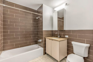 Unit bathroom, bathtub/shower, vanity with storage, sink with storage underneath, tile floor, slate colored subway tile on walls.