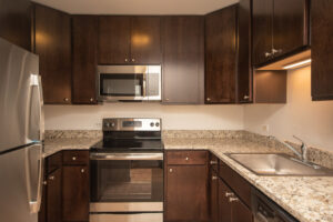 Unit Kitchen, Granite Countertops, Stainless Steel Appliances, Dark Brown Cabinetry, Wood Floors.
