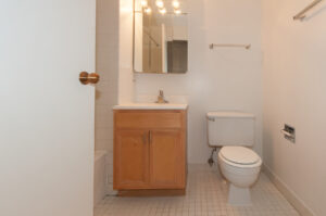 Unit Bathroom, tile floor, light brown cabinets, well lit vanity.