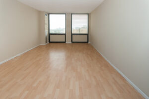 Unit Living Room, 2 large windows, wood floors, tan colored walls.