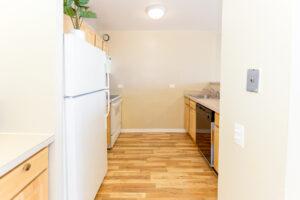 Unit Kitchen, wood floors, white appliances, light brown cabinetry.