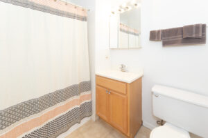 Unit Bathroom, well lit vanity mirror, light brown cabinets, towel racks.