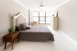 Unit bedroom, wood floors, queen size bed, dark brown nightstands, floor to ceiling windows.