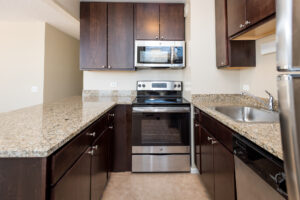 Interior Kitchen, granite countertops, stainless steel appliances, tile floor. dark brown cabinetry.