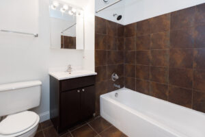 Interior Bath, earth toned tile, well lit vanity mirror, bath/shower.