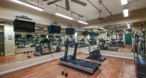 Interior Lincoln Park Plaza's Fitness Center, Wood Floors, Mirrored walls, Multiple Mounted TVs, Treadmills, Stationary bikes, Ellipticals, Free-Weights.