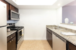 Unit Kitchen, tile floor, granite countertops, stainless steel appliances, dark brown cabinetry.