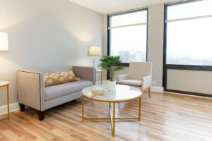 Unit Living room, Wood floors, 2 large windows with view of downtown chicago, 2 person couch and 2 chairs around large round marble coffee table.