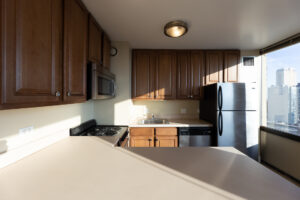 Unit Kitchen, dark brown cabinets, stainless steel appliances, tile floor.