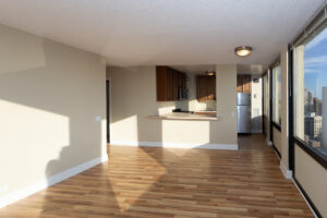 Unit Living room, wood floors, Breakfast bar attached to kitchen, naturally lit.