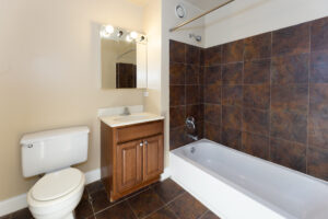 Unit Bathroom, tile floor, dark brown cabinets, well lit vanity mirror.