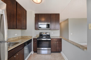 Interior Unit Kitchen, granite countertops, stainless steel appliances, dark brown cabinets.