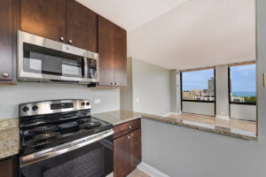 Interior Unit Kitchen, attached to living room, granite countertops, stainless steel appliances, dark brown cabinets.