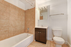 Interior Unit Bathroom, bathtub/shower, well lit vanity mirror, dark brown cabinets, tile floor.
